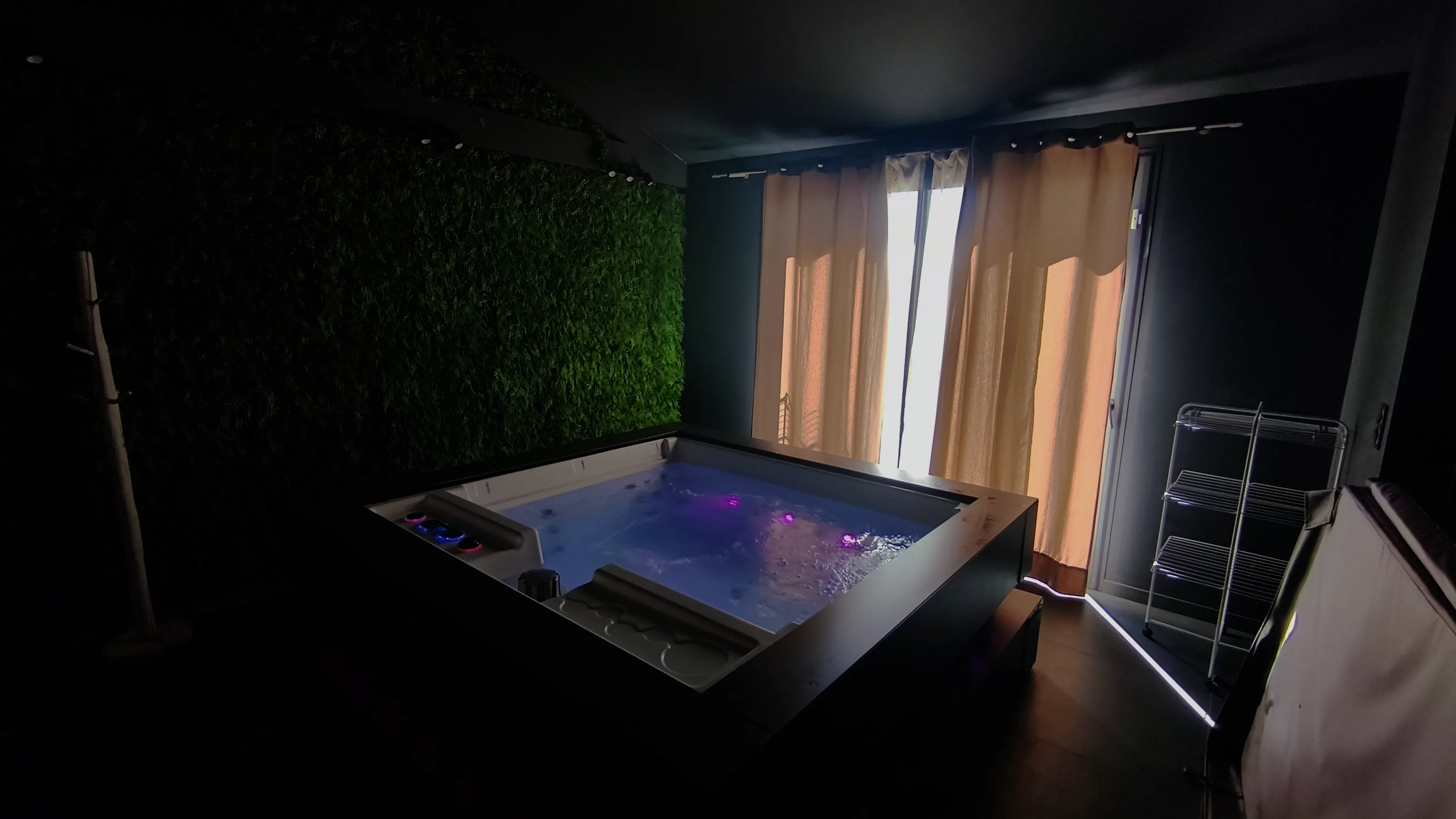 Le spa cube éclairé, devant le mur végétal et la baie