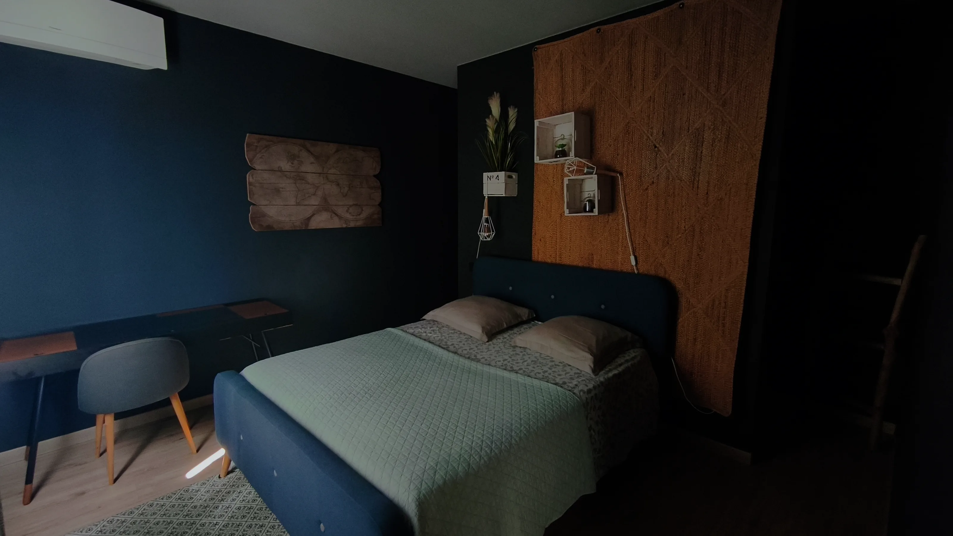 La chambre : tête de lit bleue, panneau de jute, bureau