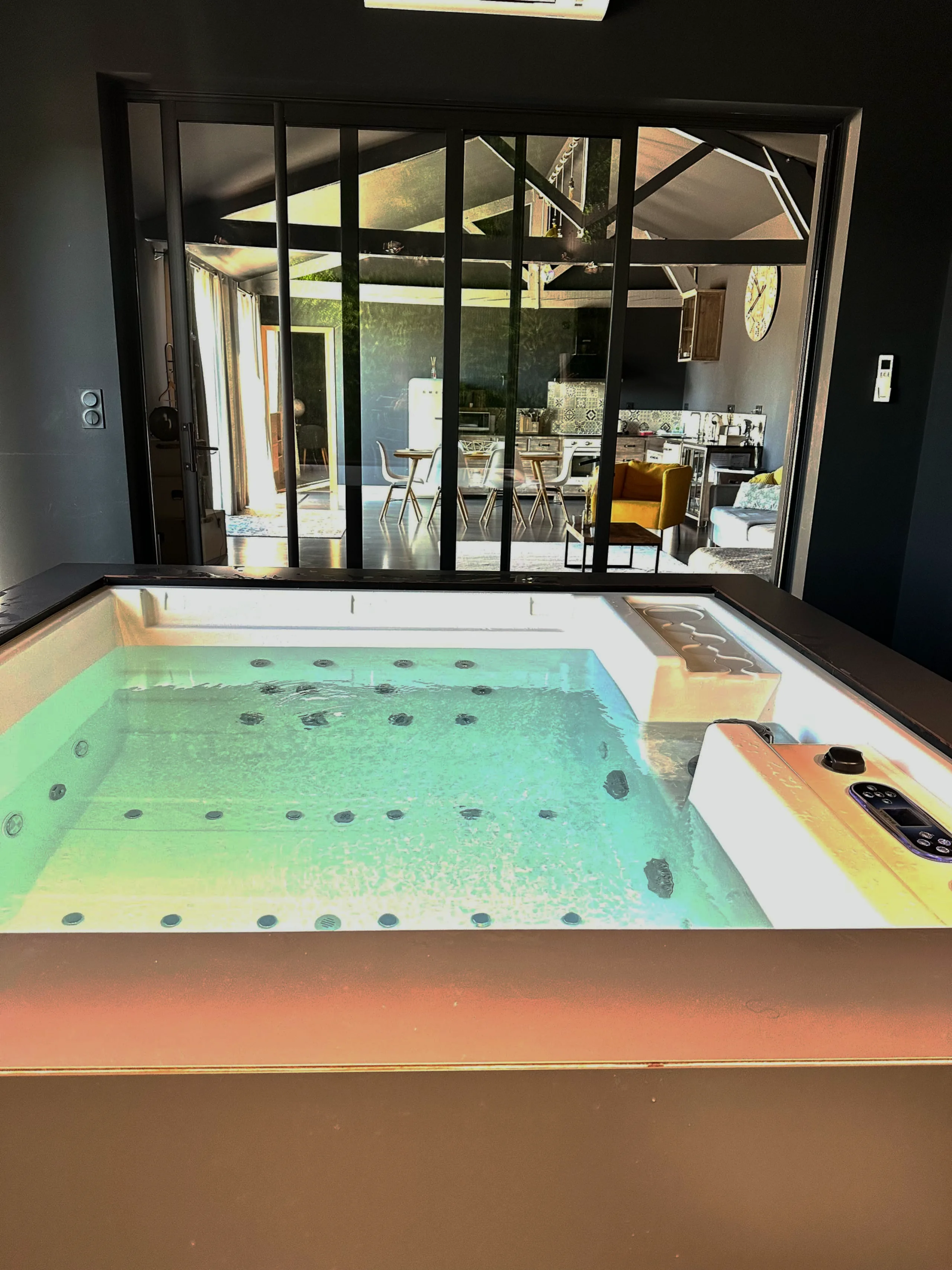 Le spa cube éclairé, et derrière la verrière, la cuisine du loft
